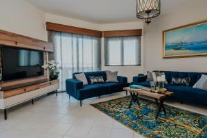 a living room with blue couches and a tv at Villa Artemis, Wine Dark Sea Villas in Rodia