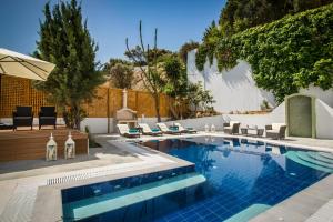 a swimming pool in a backyard with chairs and an umbrella at Villa Artemis, Wine Dark Sea Villas in Rodia