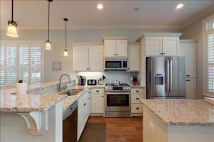 a kitchen with white cabinets and stainless steel appliances at Poolside Cottage 57 in Jekyll Island