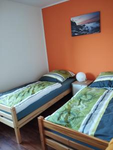 2 Einzelbetten in einem Zimmer mit orangefarbenen Wänden in der Unterkunft Apartment Landliebe im Weserbergland in Bevern