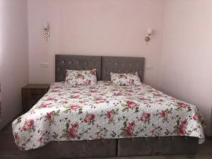 a bedroom with a bed with a floral comforter and pillows at Syune Syunick Shinuhayr in Shinuhayr