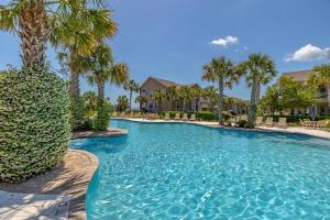 a swimming pool with palm trees in a resort at Garden Cottage 62 in Jekyll Island