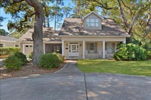 a white house with a tree and a driveway at Breezy Cottage in Jekyll Island