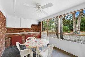 uma cozinha com mesa, cadeiras e janelas em Carole Cottage em Jekyll Island