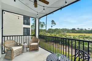 a porch with chairs and a table and a fence at Moorings 104 in Jekyll Island