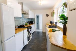 eine Küche mit weißen Schränken und einer Holzarbeitsplatte in der Unterkunft Stylish 6-Bedroom House, Ideal for Contractors! in Monkwearmouth + 133 Fotos