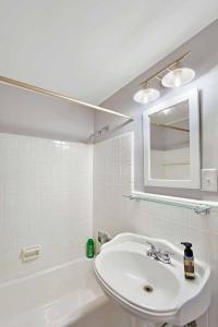 a white bathroom with a sink and a mirror at Brice Sea Shell Stay in Jekyll Island