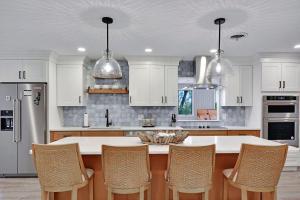 eine Küche mit weißen Schränken und einem Tisch mit Stühlen in der Unterkunft A Wave From It All in Jekyll Island