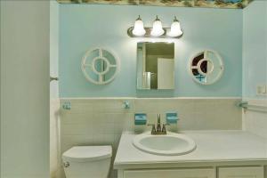 a bathroom with a sink and a toilet and mirrors at Lanier Cottage in Jekyll Island +16 photos