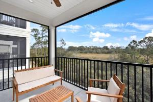 a porch with a bench and chairs on a balcony at Moorings 206 in Jekyll Island
