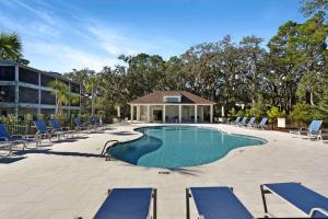 a swimming pool with lounge chairs and a building at Moorings 107 in Jekyll Island