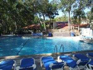 a large swimming pool with blue chairs in it at Villa 453 in Jekyll Island