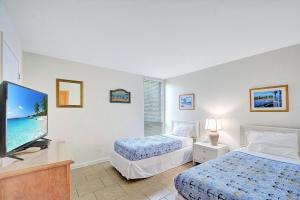 a bedroom with two beds and a flat screen tv at Villa 107 in Jekyll Island
