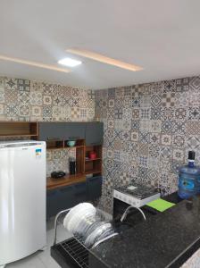 a kitchen with a white refrigerator and tiles on the wall at Aconchego do Áureo in Pacoti