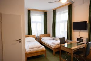 a room with two beds and a desk and a table at Aparthotel Mariazellerhof in Sankt Pölten