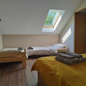 a attic bedroom with two beds and a window at Apartamenty u Gołębiewskich in Stara Kamienica