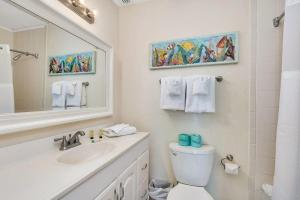 une salle de bain avec un lavabo, des toilettes et un miroir dans l'établissement Villa 379, à Île de Jekyll 18 autres photos