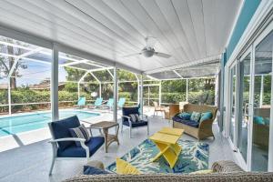 a covered porch with chairs and a swimming pool at Sandpiper Hideaway in Jekyll Island