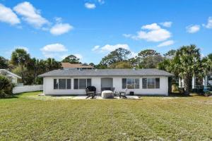 a white house with two chairs in a yard at Spring Cottage in Jekyll Island