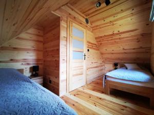 a log cabin with a bed and a window at Cisza Roztocze in Wierzchowiny