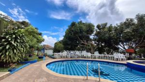 a pool at a resort with white chairs and trees at Villa Confort in La Mesa