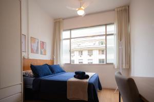 een slaapkamer met een blauw bed en een groot raam bij SUH Copacabana 43 New Confort in Rio de Janeiro