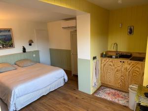a bedroom with a bed and a sink and a kitchen at Cabanon Régina in Lège-Cap-Ferret