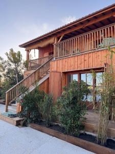a wooden house with a balcony and some plants at Cabanon Régina in Lège-Cap-Ferret