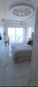 a white bedroom with a bed and a large window at Blue ocean villa in Asilah