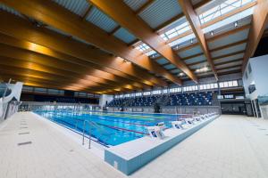 a large swimming pool with chairs in a building at ÁTRIUM Apartman Kaposvár in Kaposvár