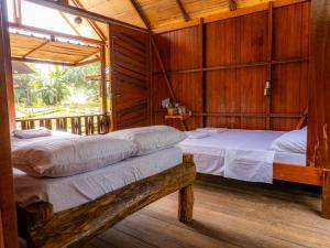 two beds in a room with wooden walls at Ecolodge Azul Paradise in Nuquí