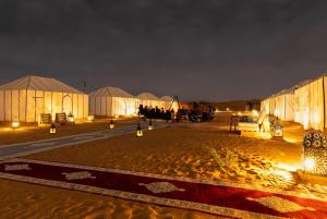 a group of tents in a field at night at Yamanda luxury camp in Merzouga