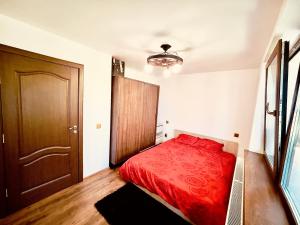 a bedroom with a red bed and a wooden door at Stefy Home Holiday in Viişoara