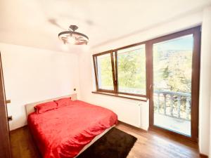 a bedroom with a red bed and a large window at Stefy Home Holiday in Viişoara