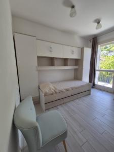 a bedroom with a bed and a chair and a window at A casa di Elena in Lesa