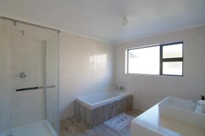 a bathroom with a tub and a shower and a sink at Tassies in Gansbaai