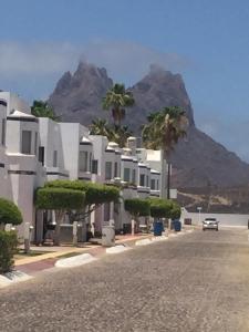 a building with palm trees and a mountain in the background at San Carlos Sonora Casa Caracol Condominio in Guaymas