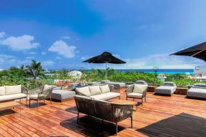 普拉亚卡门The Yucatan Playa Del Carmen, Tapestry Collection By Hilton的木制甲板上配有椅子和遮阳伞的庭院