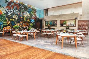 普拉亚卡门The Yucatan Playa Del Carmen, Tapestry Collection By Hilton的一间有桌椅和壁画的餐厅