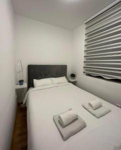 a bedroom with a white bed with two towels on it at Dolce apartman Zlatibor in Zlatibor
