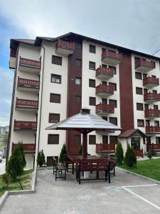 a building with a picnic table and an umbrella at Dolce apartman Zlatibor in Zlatibor