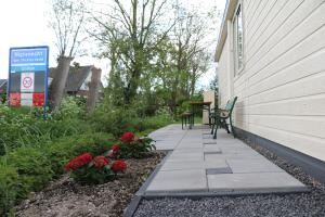 eine Terrasse mit zwei Bänken und Blumen neben einem Haus in der Unterkunft Landelijk gelegen chalet aan de Vecht vlakbij Amsterdam in Nigtevecht + 22 Fotos