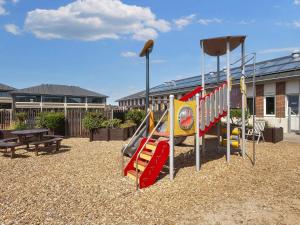 a playground with a slide and a table and a bench at 4 person holiday home on a holiday park in Fanø in Fanø