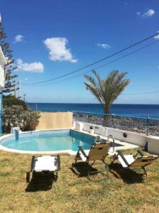a swimming pool with two chairs and the ocean at Maison fatha in Kelibia