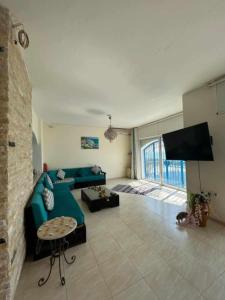 a living room with a blue couch and a flat screen tv at Maison fatha in Kelibia