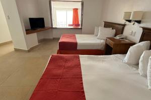 a hotel room with two beds and a television at Spacious, standard with beach access & wifi! in Puerto Vallarta