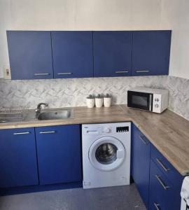 eine Küche mit blauen Schränken und einer Waschmaschine in der Unterkunft Prime city centre apartment! in Manchester
