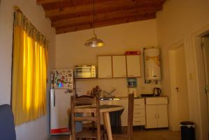 Una pequeña cocina con una mesa y un refrigerador. en Cabaña La Resolana, en Tandil