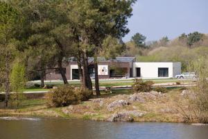 a white house next to a body of water at Auberge des VoyaJoueurs in Monteneuf