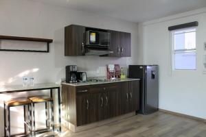 a kitchen with wooden cabinets and a black refrigerator at Lofts Las Fuentes in Guadalajara